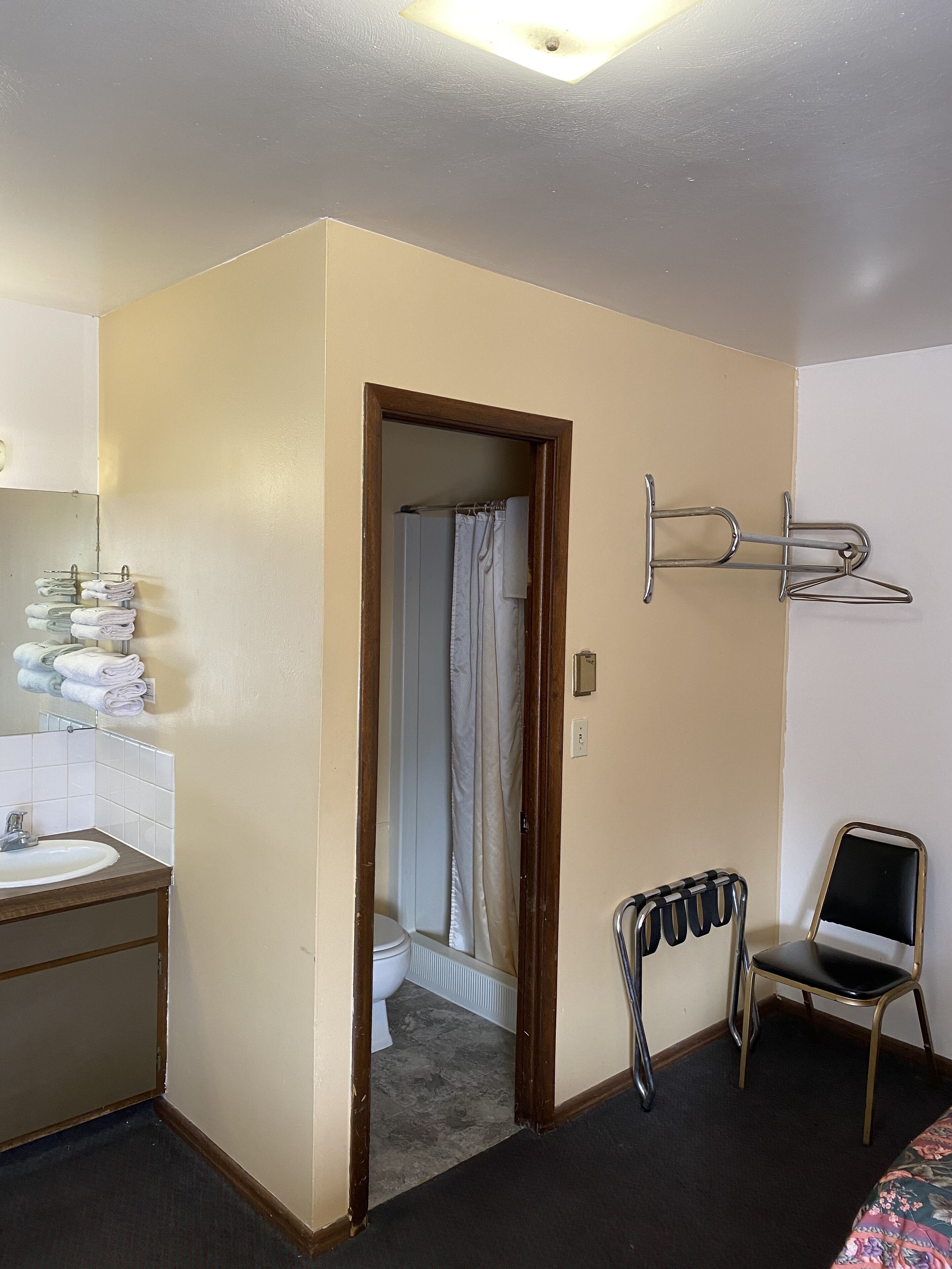 Quarto de hotel com banheiro, pia, cadeira e cama.