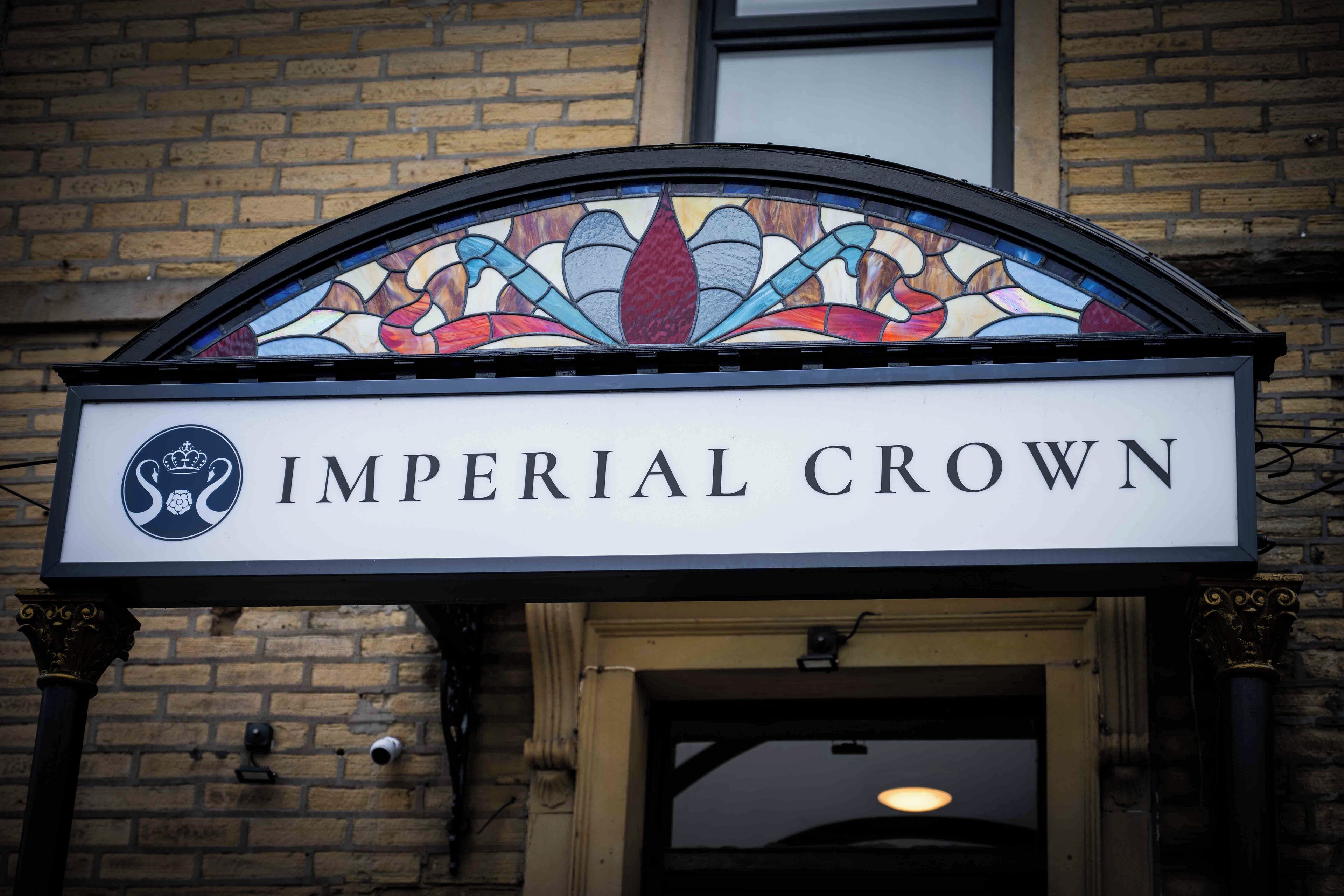A sign with "IMPERIAL CROWN" and a crest above a doorway.