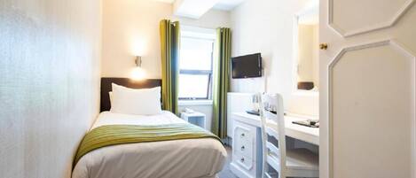 A hotel room with a bed, a desk, a chair, a television, and a window with curtains.