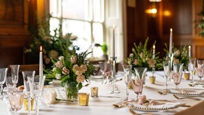 Une table à manger élégante, dressée avec de la verrerie, des bougies et des compositions florales.