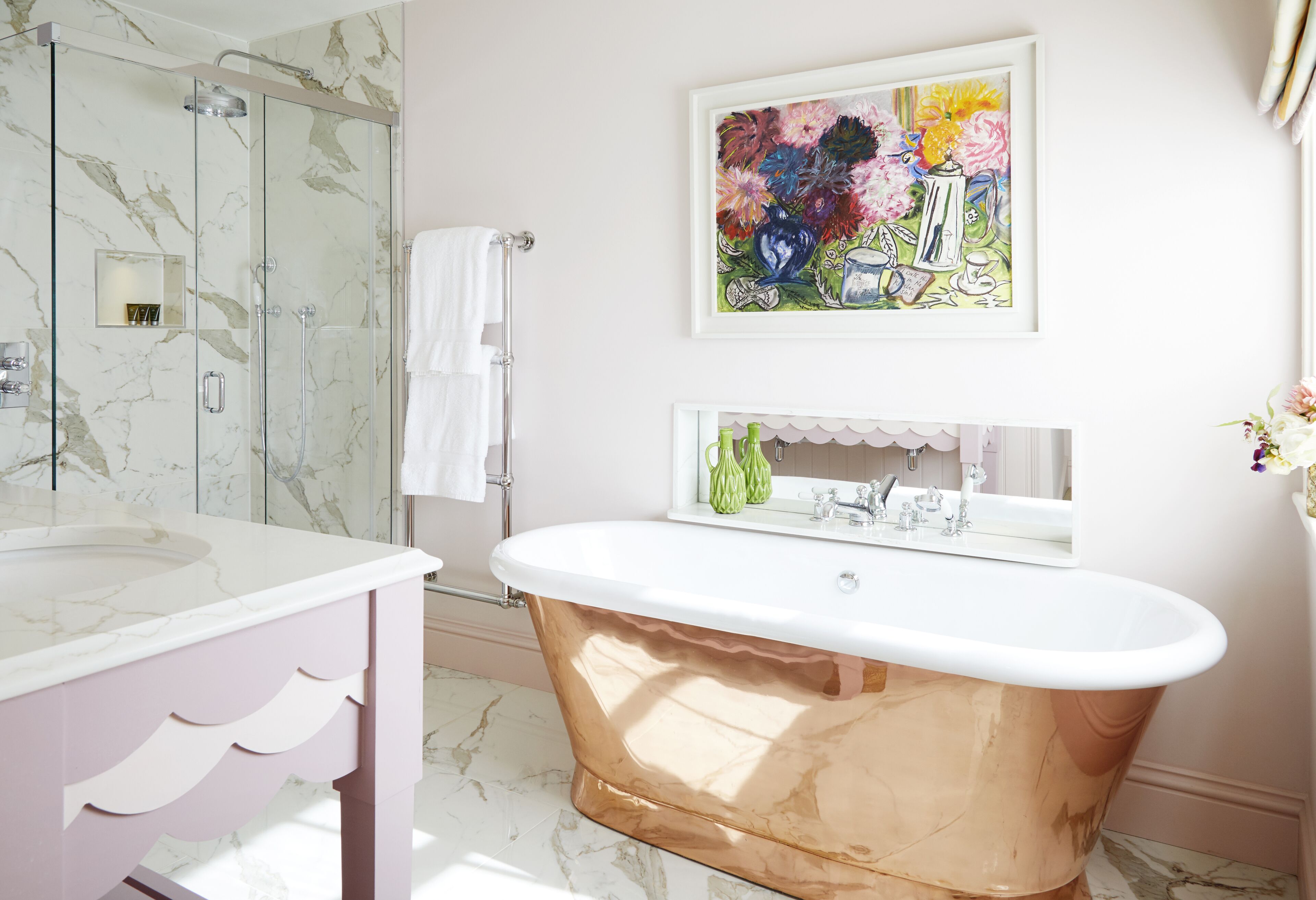 Un bagno con doccia in marmo, lavabo bianco, vasca da bagno in rame e un'opera d'arte colorata appesa al muro.