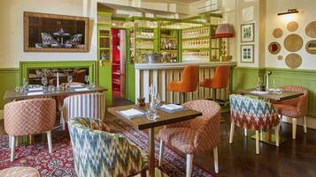 Un restaurante con barra, varias mesas y sillas.