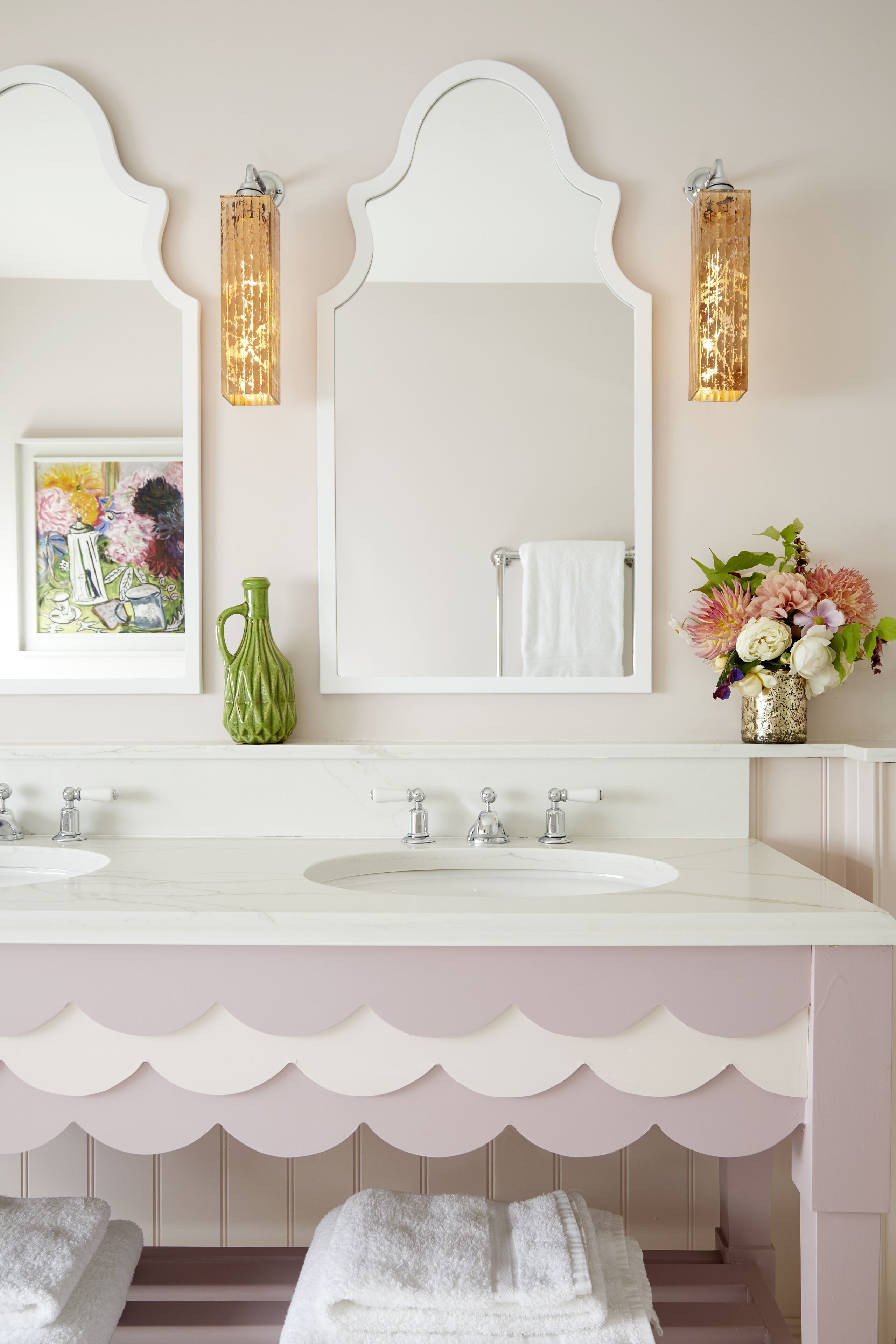 Une salle de bain avec deux lavabos, un grand miroir et des appliques murales décoratives.