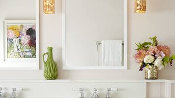 Une salle de bain avec deux lavabos, un grand miroir et des appliques murales décoratives.