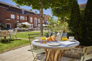 A round table set outdoors with breakfast items, a glass of orange juice, and a croissant. - The Grosvenor Stockbridge (Stockbridge)