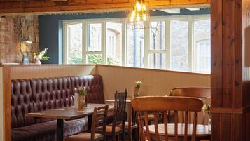 A cozy restaurant with a wooden interior, a leather booth, wooden tables, and chairs.