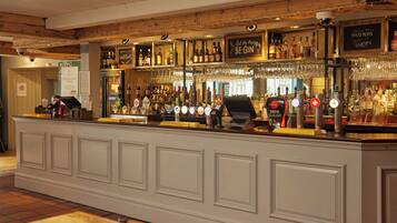 A bar area with a counter, shelves of bottles, and a sign that reads "Let the fun begin."
