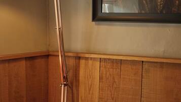 A corner room with a floor lamp, a framed picture of wheat fields, and wooden paneling.
