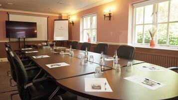 A conference room with a long table, chairs, a projector screen, and a whiteboard.
