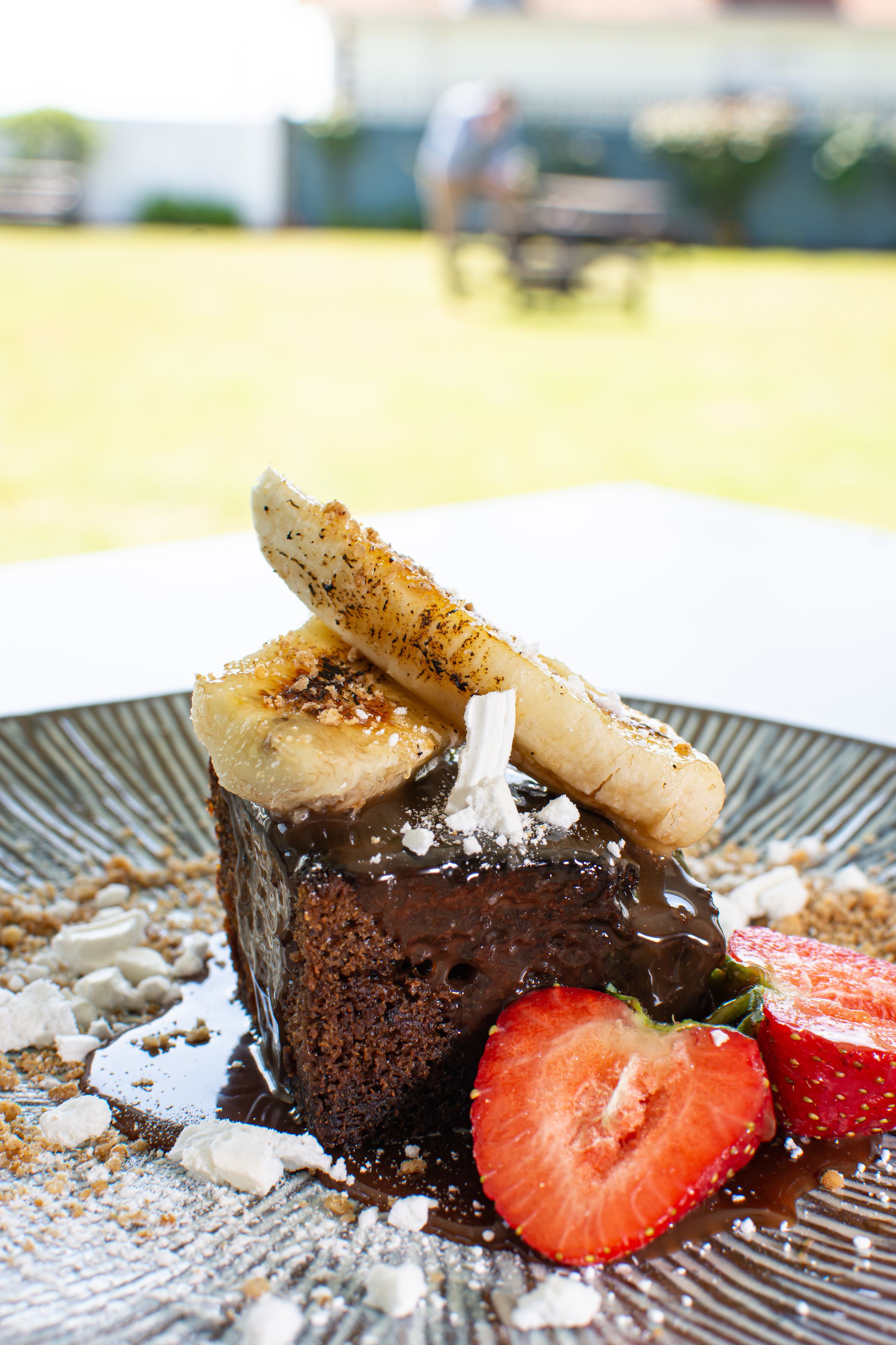 A dessert with chocolate cake, banana slices, and strawberries on a plate.