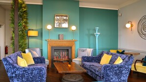 A cozy living room with two patterned sofas, a coffee table, and a fireplace. - Kingscliff Hotel (Clacton-on-Sea)