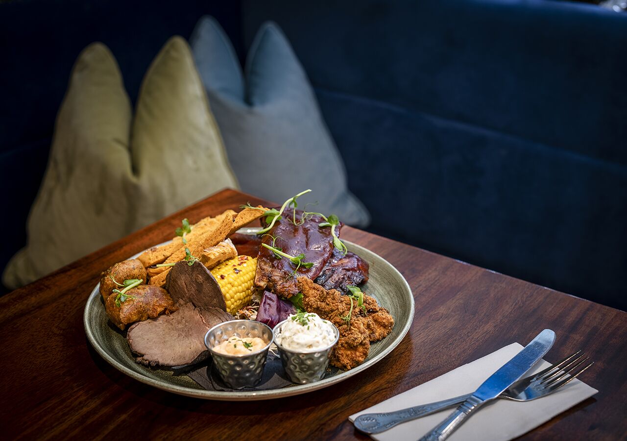 A plate of food with various items including meat, vegetables, and sauces on a table.