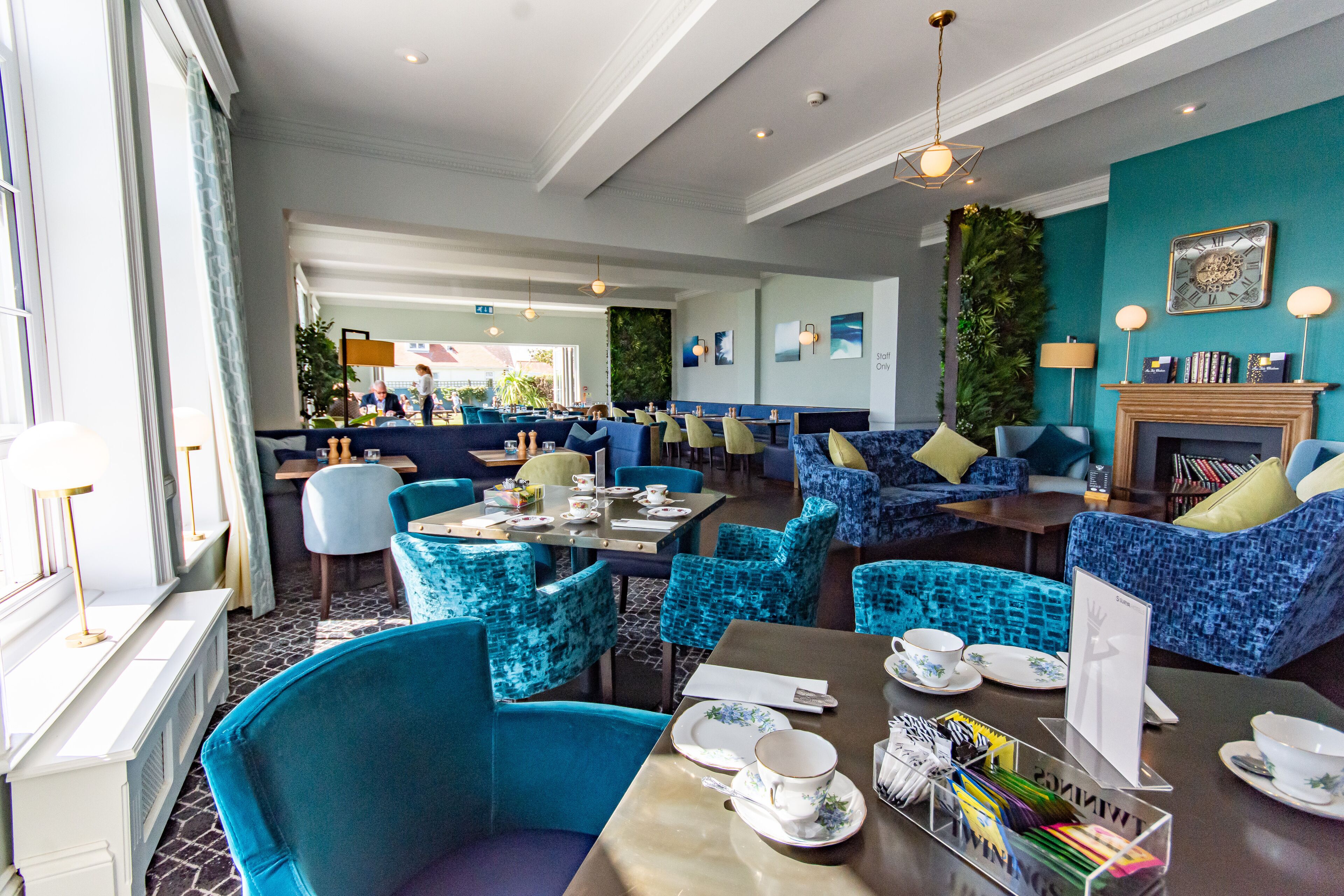 A hotel lobby with blue upholstered seating, a fireplace, and a view of the street.
