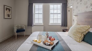 A hotel room with a neatly made bed, a tray of breakfast items, and a chair. - Kingscliff Hotel (Clacton-on-Sea)