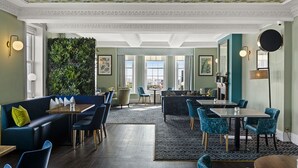 A spacious hotel lobby with a central seating area, a large window offering a view, and a green wall with a vertical garden. - Kingscliff Hotel (Clacton-on-Sea)
