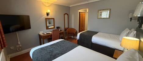 A hotel room with two beds, a desk with a chair, a TV, and a mirror.