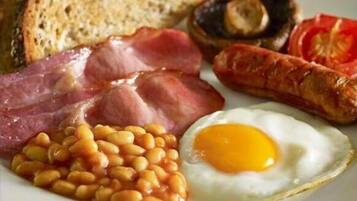 A plate of breakfast food including eggs, beans, bacon, sausages, mushrooms, and toast.