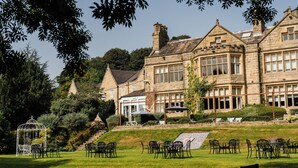 A large stone building with multiple windows and a covered outdoor seating area. - Hollins Hall Hotel, Spa & Golf (Shipley)