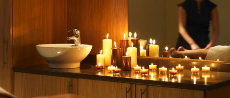Ein Badezimmer mit einem Holzausziehtisch, einem Waschbecken und mehreren Kerzen auf der Ablagefläche.