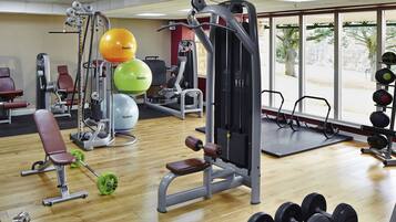 A gym with various exercise equipment, including a bench, dumbbells, and exercise balls.