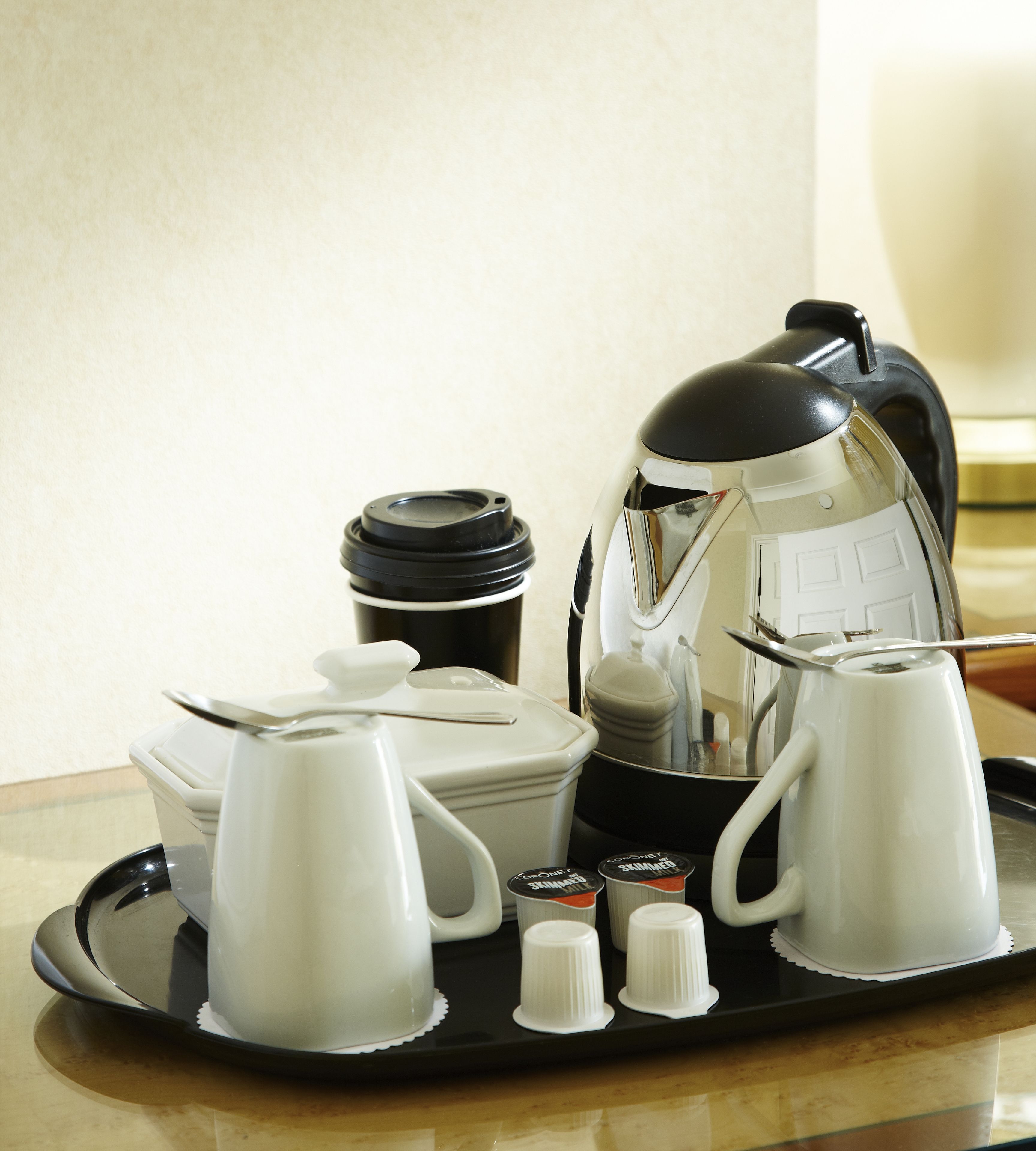 A tray with a coffee maker, a teapot, a cup, a mug, and a thermos.