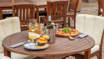 Ein runder Holztisch mit Pizza, Burger und Getränken.