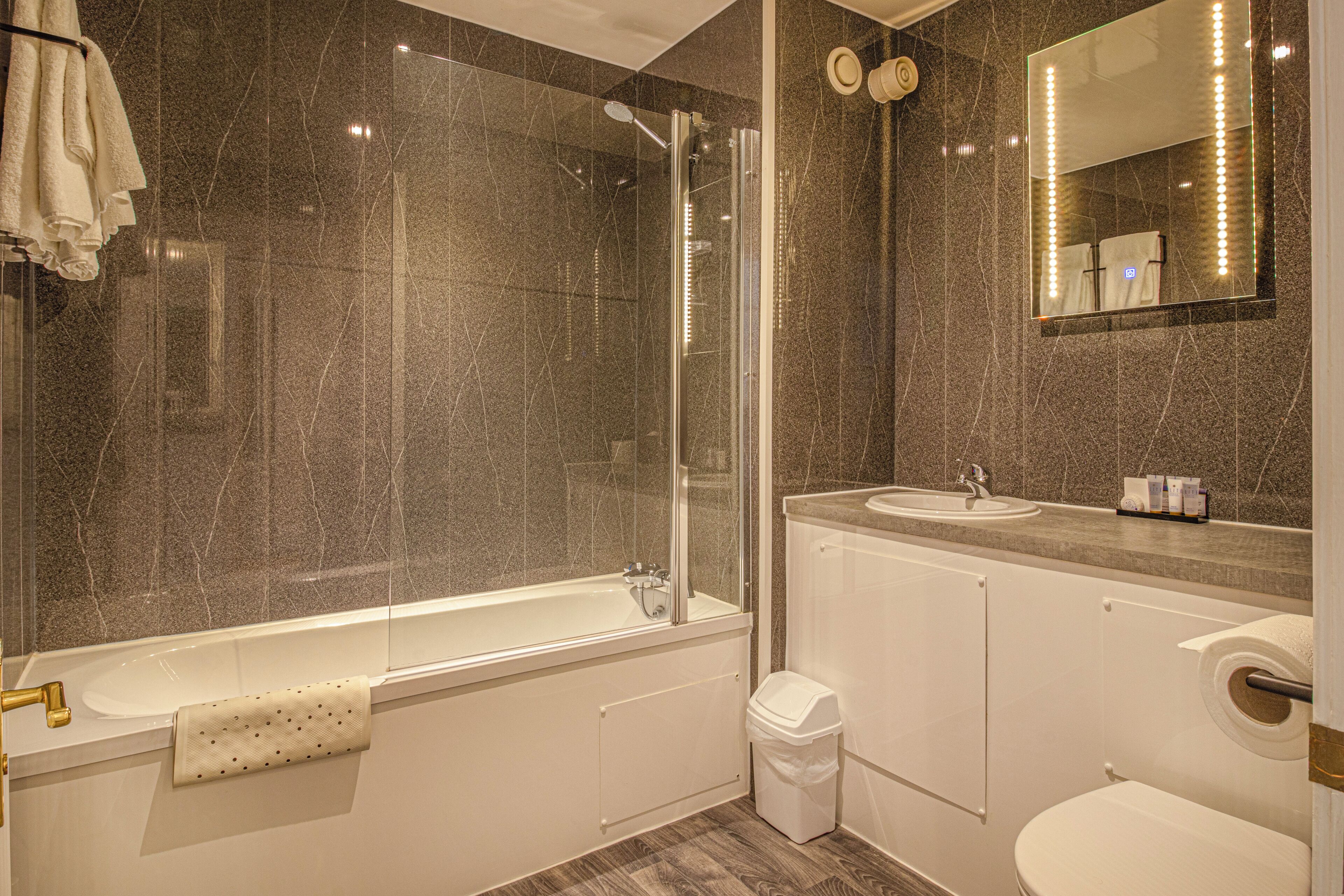 A modern bathroom with a glass-enclosed shower, a standalone bathtub, a vanity with a sink, and a toilet.
