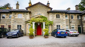 A stone building with a red door, columns, and a gravel driveway.