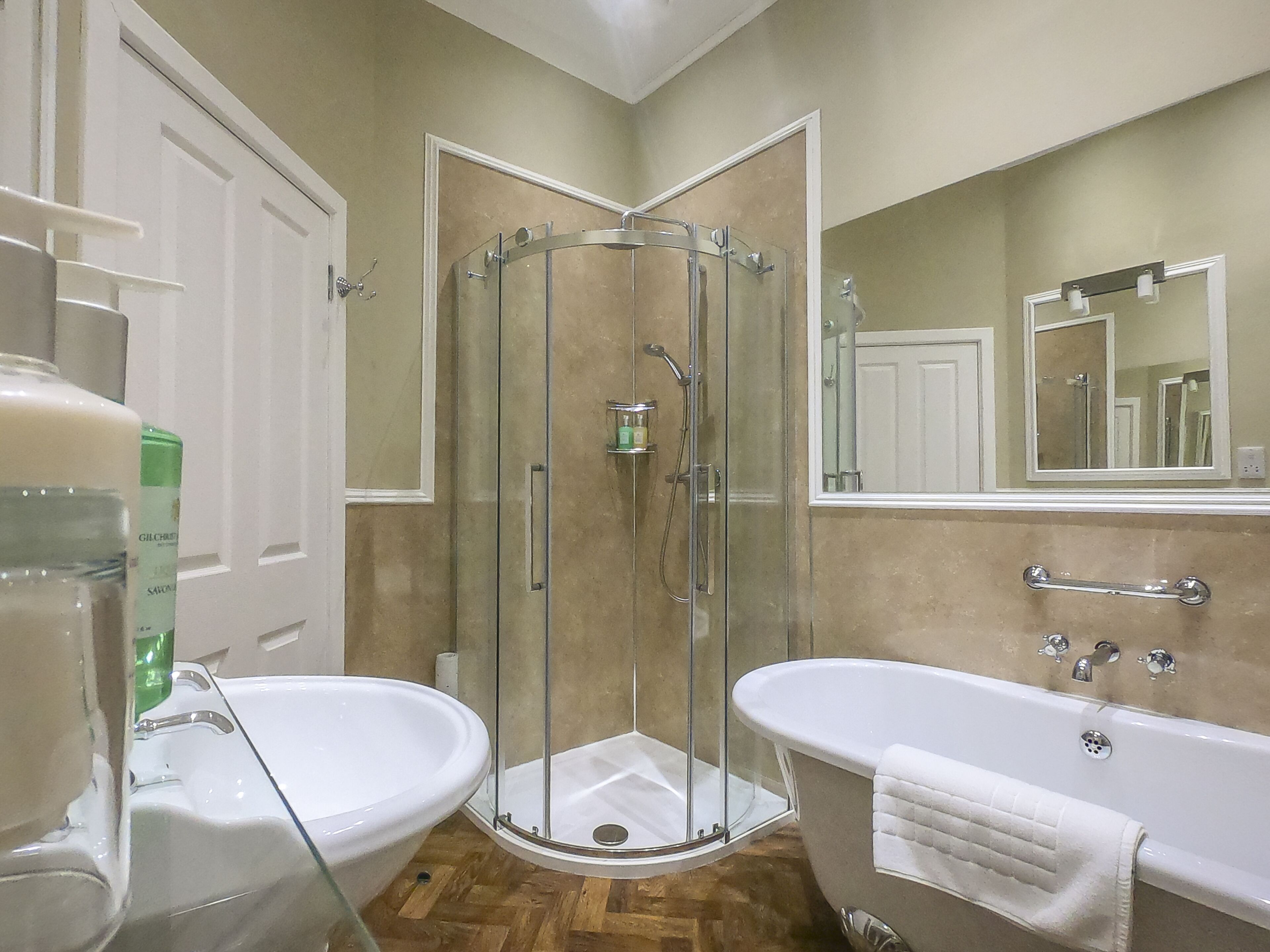 A bathroom with a glass-enclosed shower, a bathtub, and a sink.