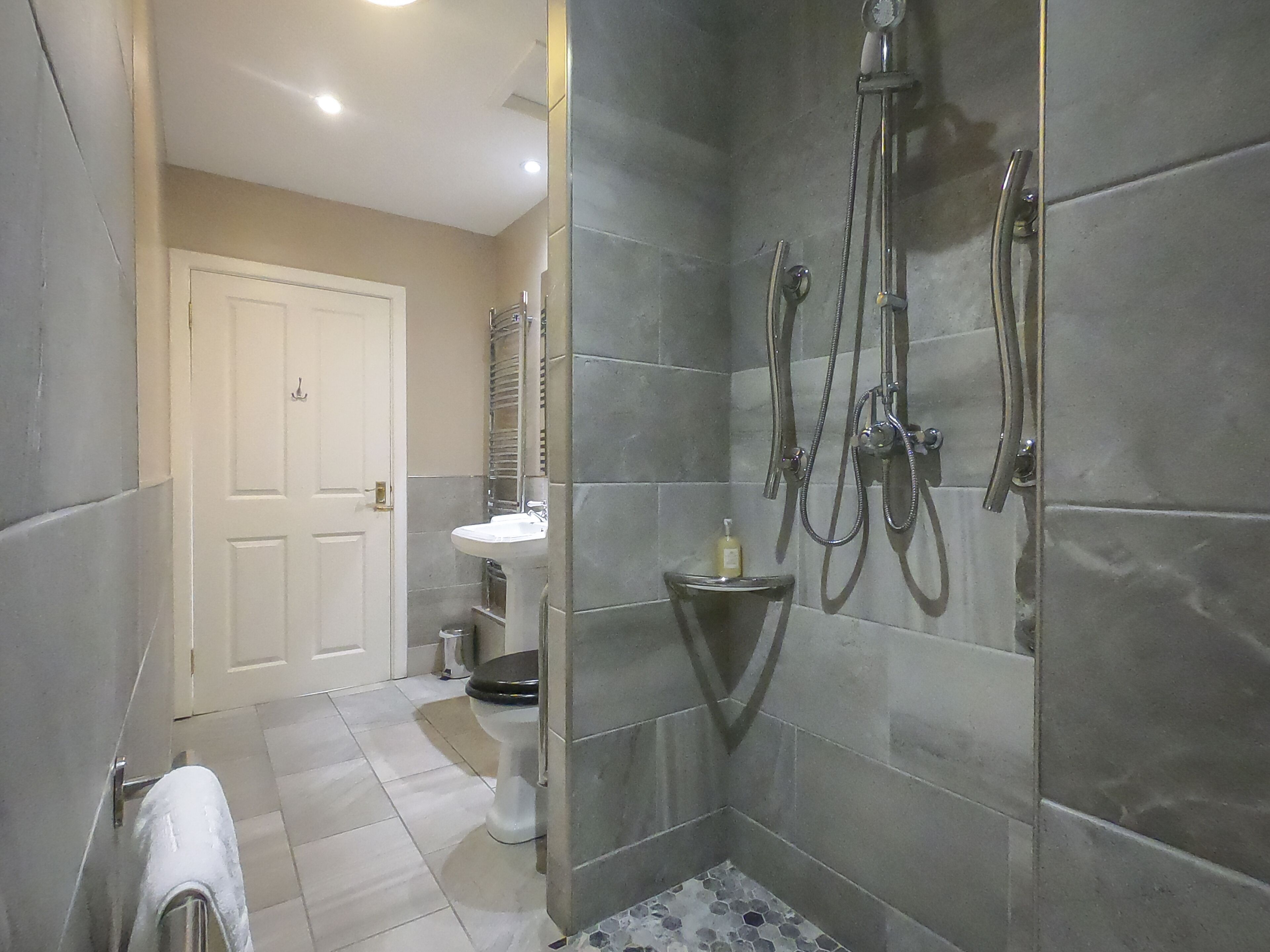 Un baño moderno con ducha envuelta en vidrio, un lavamanos blanco y un inodoro.