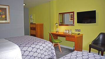 A hotel room with two beds, a desk with a chair, a television, and a mirror.