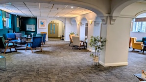 A hotel lobby with a carpeted floor, seating areas, and a reception desk. - Quality Hotel Coventry (Coventry)