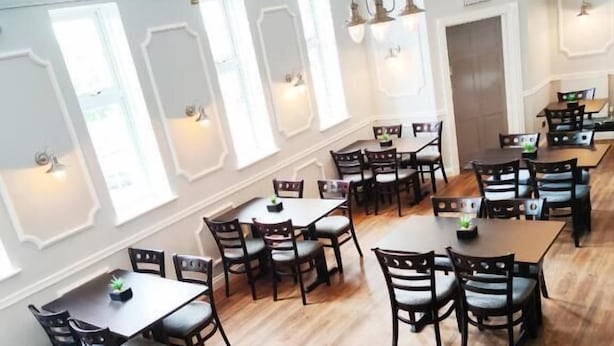 A spacious dining area with multiple tables and chairs, large windows with decorative wall sconces, and a wooden floor. - Quality Hotel Coventry (Coventry)
