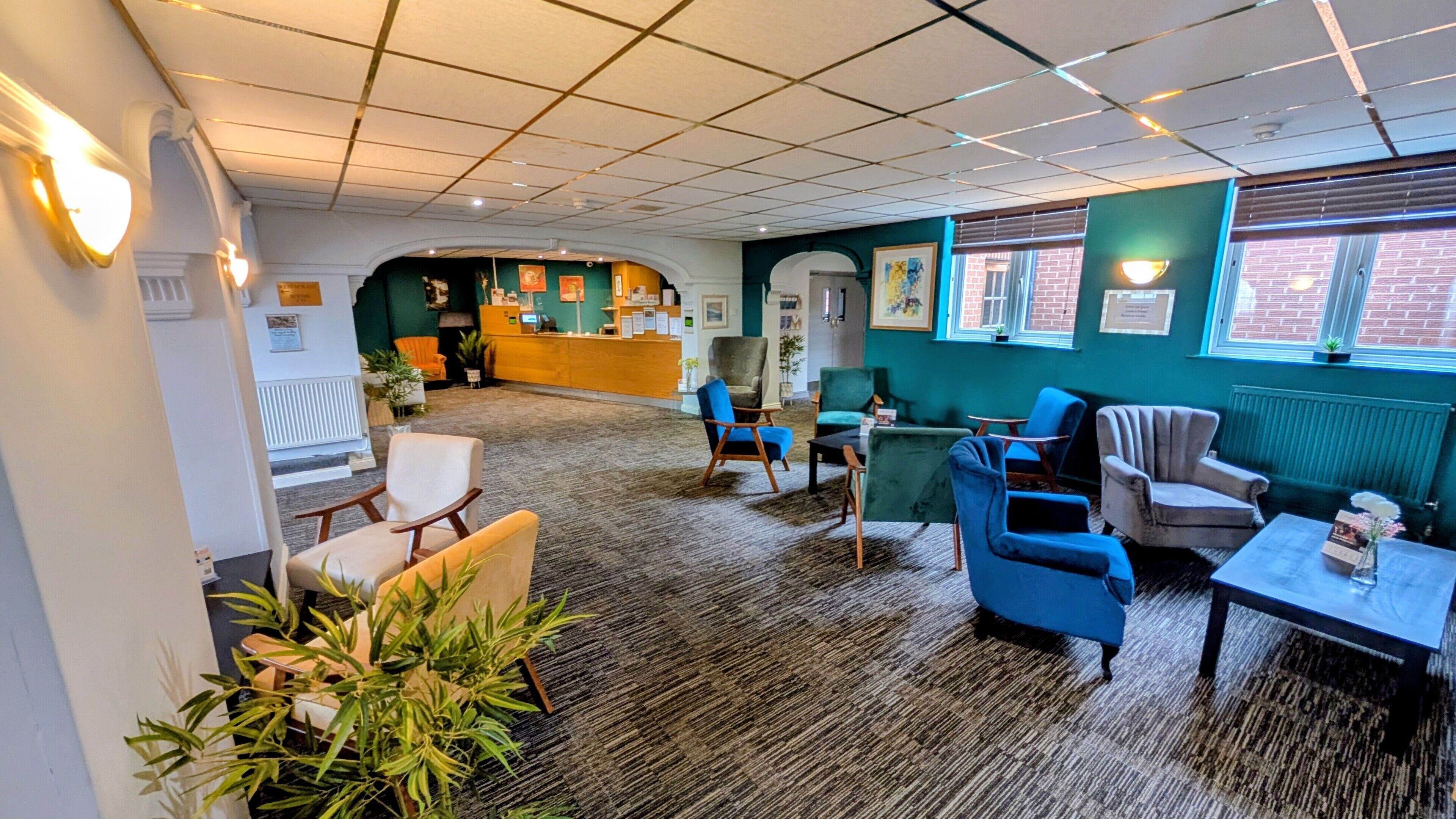 A hotel lobby with a reception desk, seating area, and large windows.
