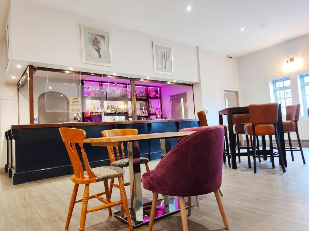 A bar area with a counter, bar stools, and a seating area with chairs.