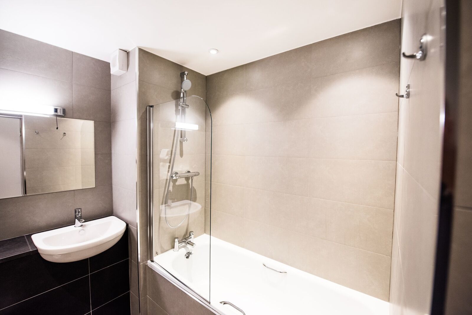 A modern bathroom with a glass-enclosed shower, a white sink, and a large bathtub.