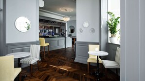 A bar area with a wooden herringbone floor, bar stools, and a bar counter.