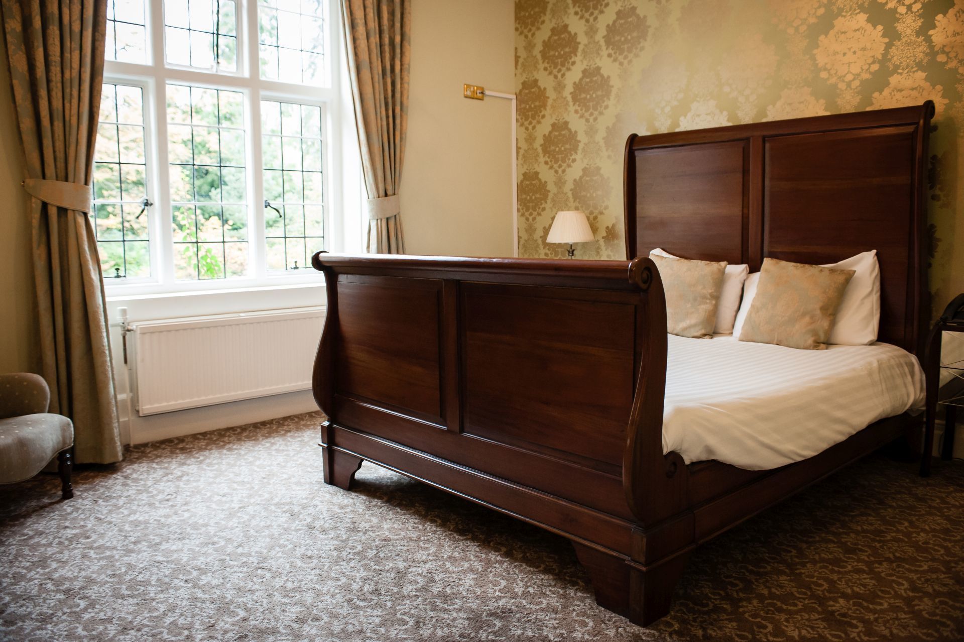 A four-poster bed with a wooden headboard and footboard, a white bedspread, and two pillows.