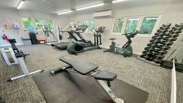 A gym with treadmills, elliptical machines, a bench press, and a rack of dumbbells.