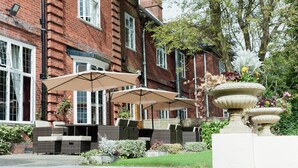 A courtyard with outdoor seating, a brick building, and a decorative fountain.