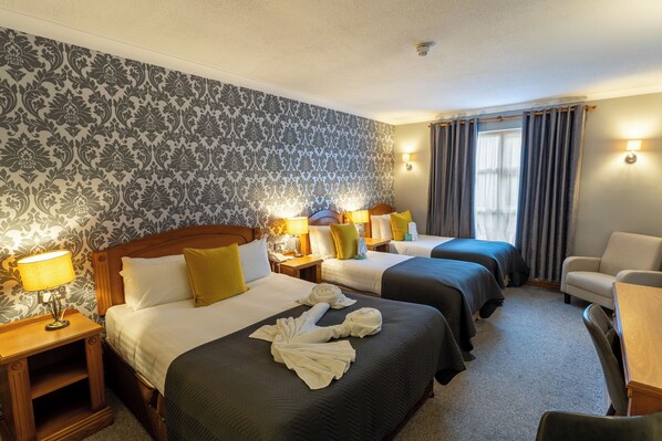 A hotel room with two beds, a desk, a chair, and a lamp. - Majestic Hotel (Tramore)