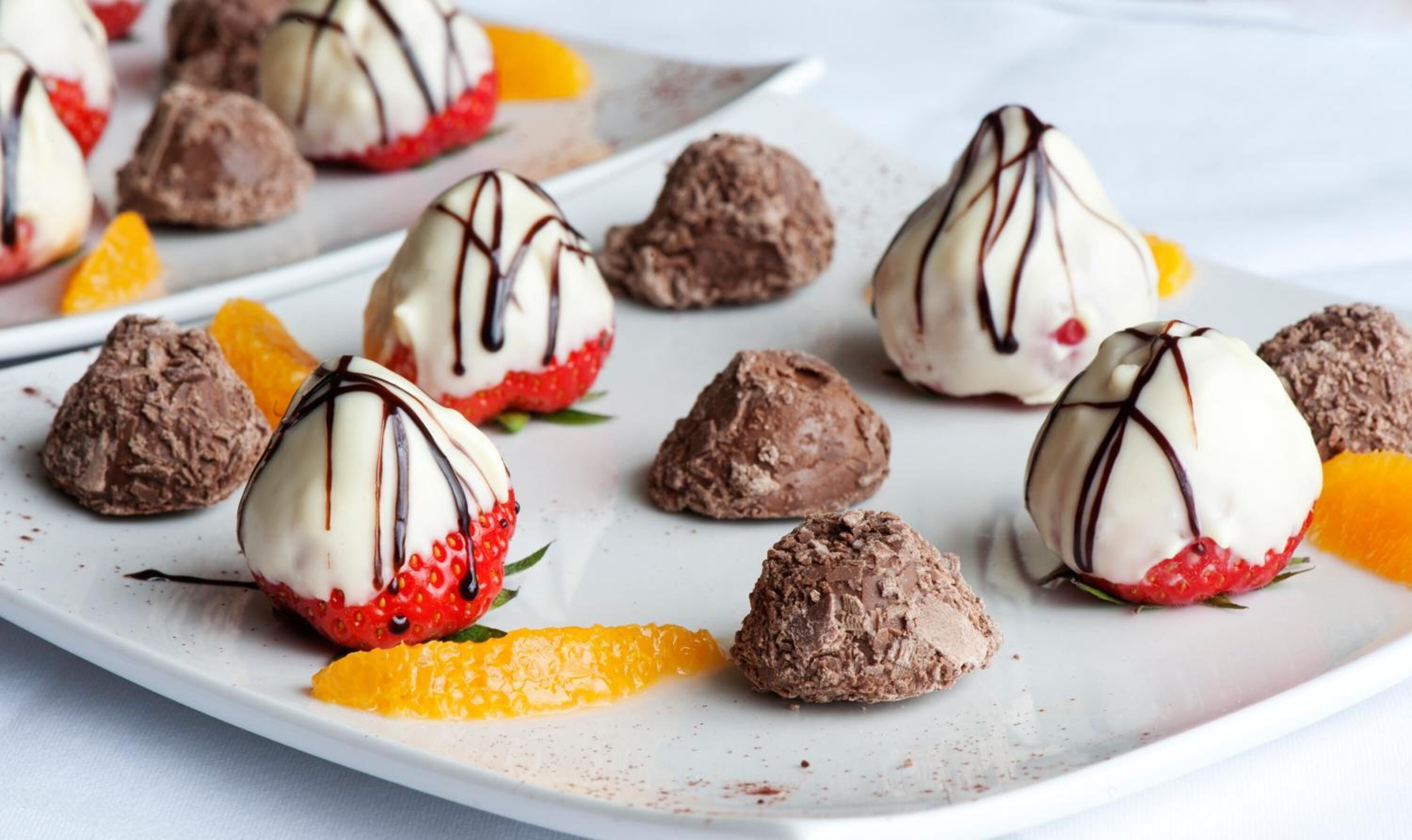 A dessert plate with chocolate truffles and strawberries.