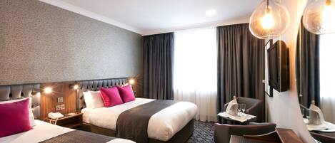 Quarto de hotel com duas camas, uma escrivaninha, uma cadeira, um telefone e um espelho.