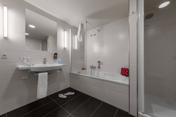 Un baño moderno con ducha acristalada, lavabo blanco y espejo.