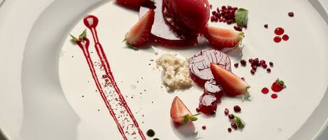 A dessert plate with strawberries, a scoop of ice cream, and a red sauce.