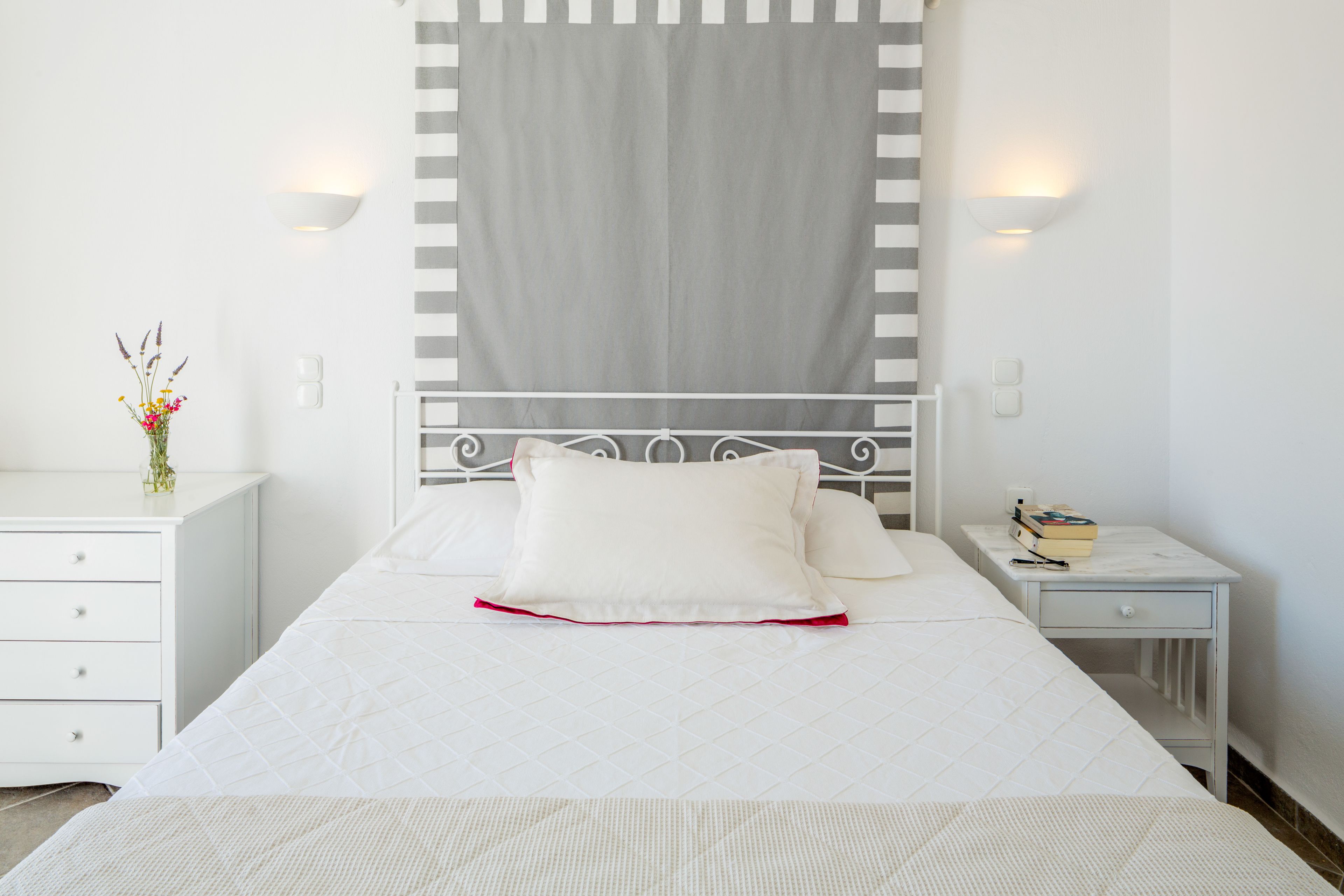 Ein ordentlich eingerichtetes Schlafzimmer mit einem Bett, Nachttischen, einem Nachtlicht und einer Wandleuchte.