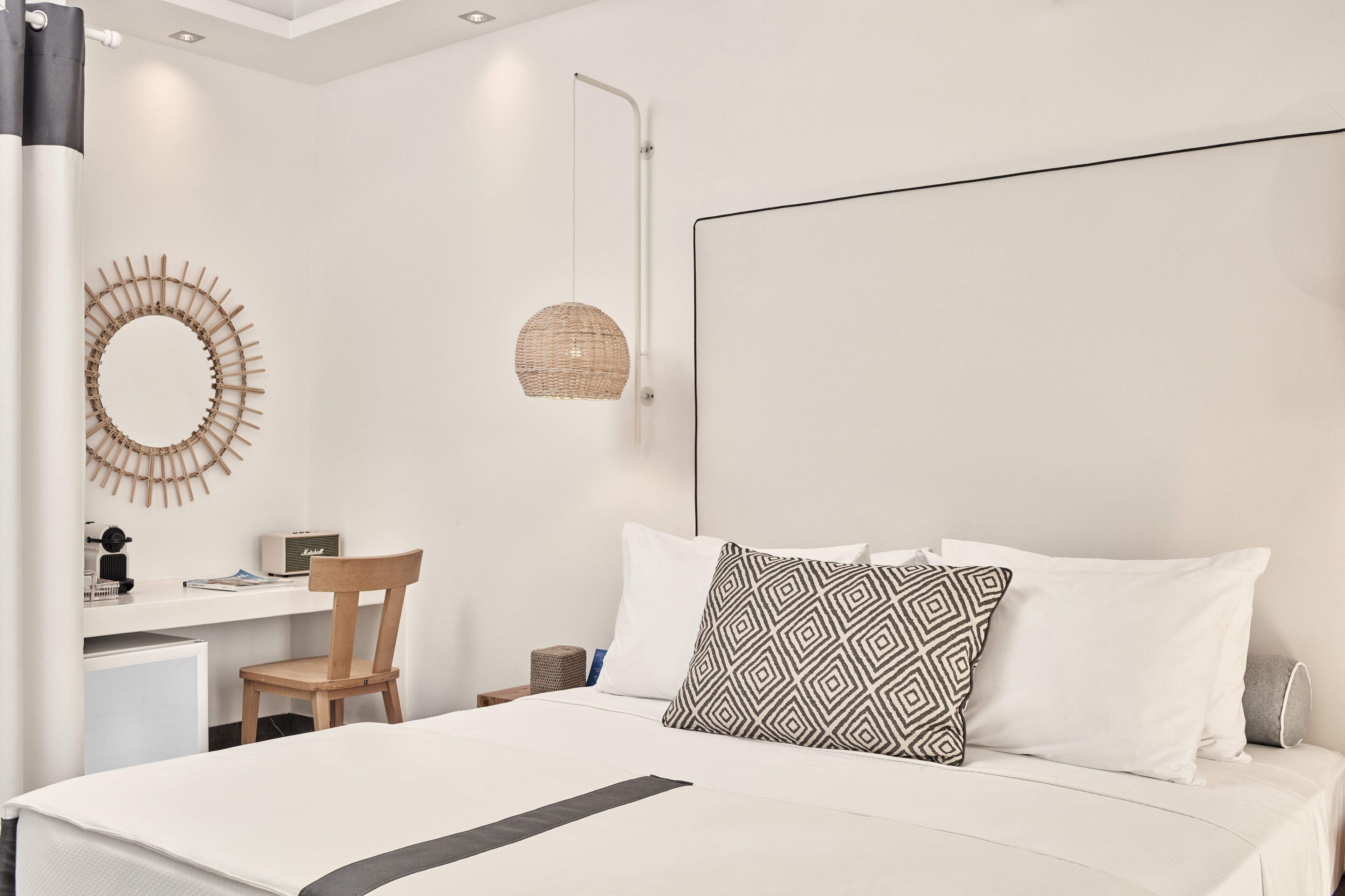 Camera da letto moderna con un letto grande, una scrivania, una sedia e uno specchio fissato alla parete.