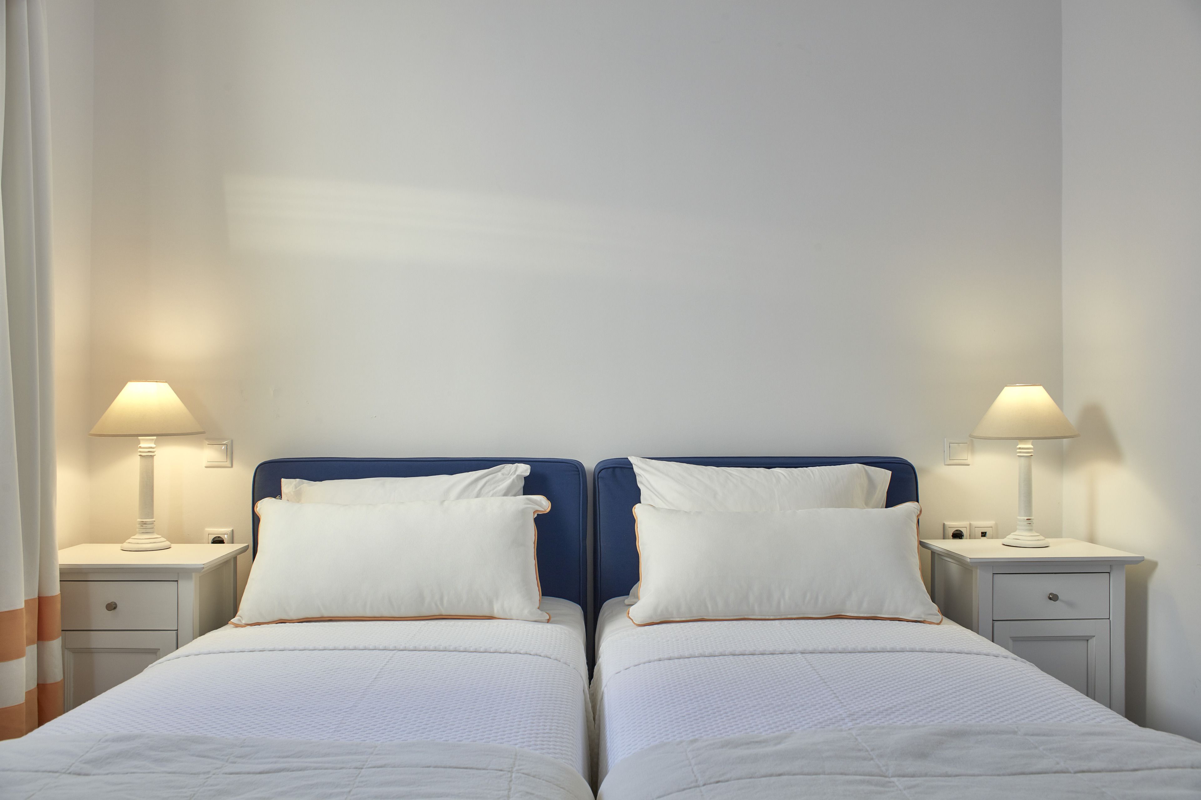 Habitación doble con dos camas individuales, cada una con mesita de noche y lámpara.