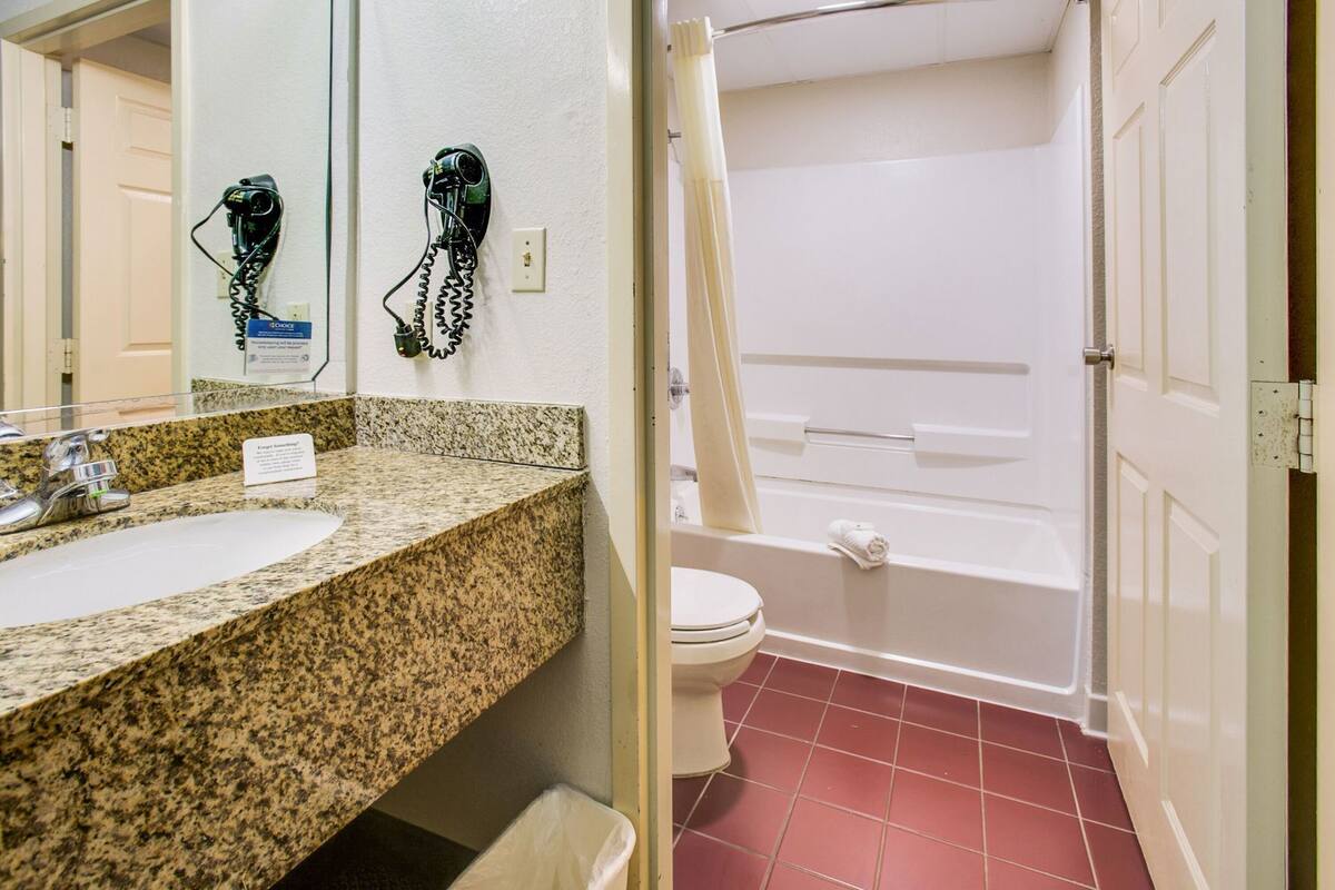 A bathroom with a granite countertop sink, a toilet, and a bathtub.