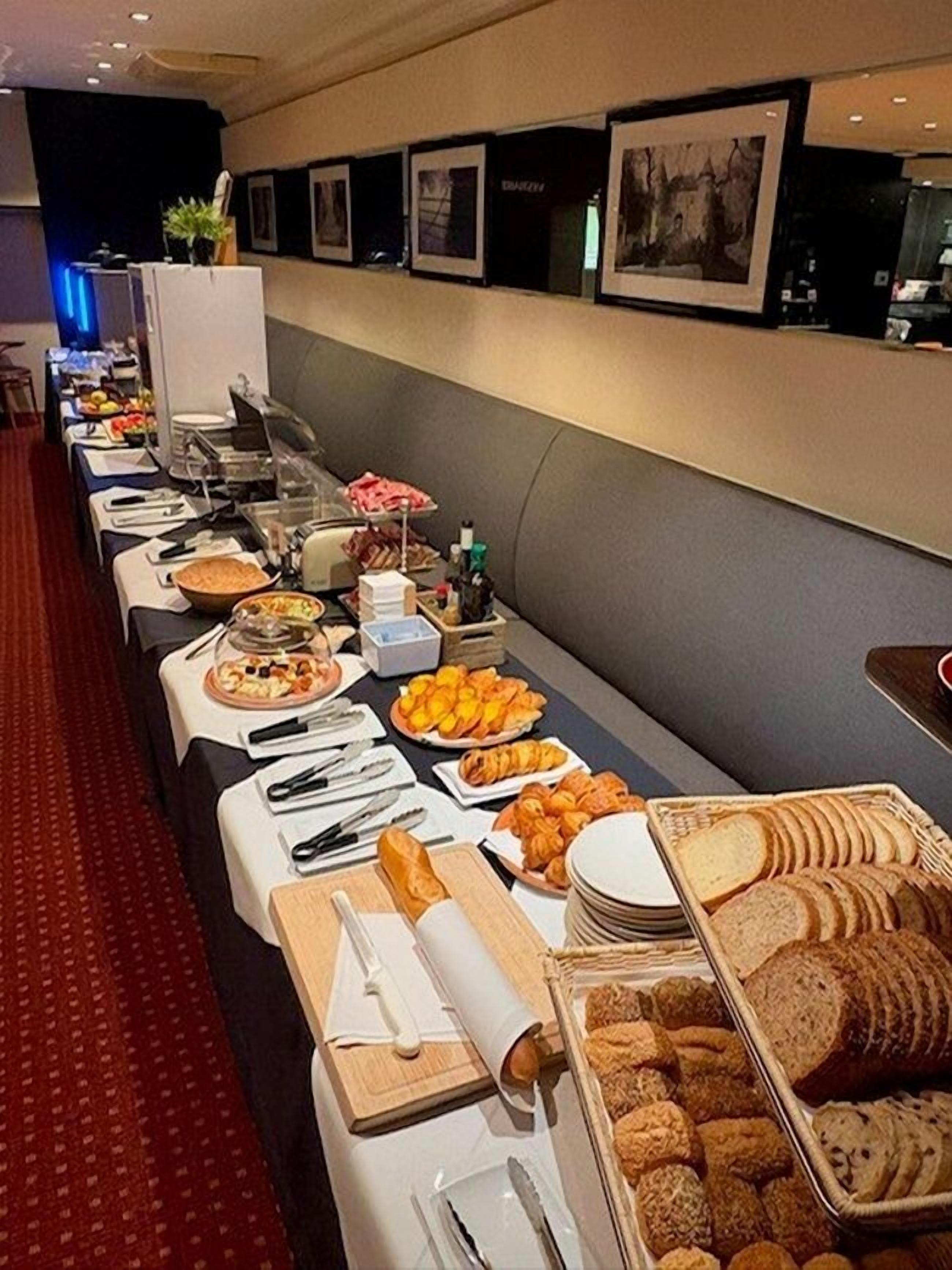 A buffet setup with various food items and utensils laid out on a table.